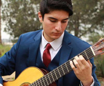 Young man outdoors playing a guitar